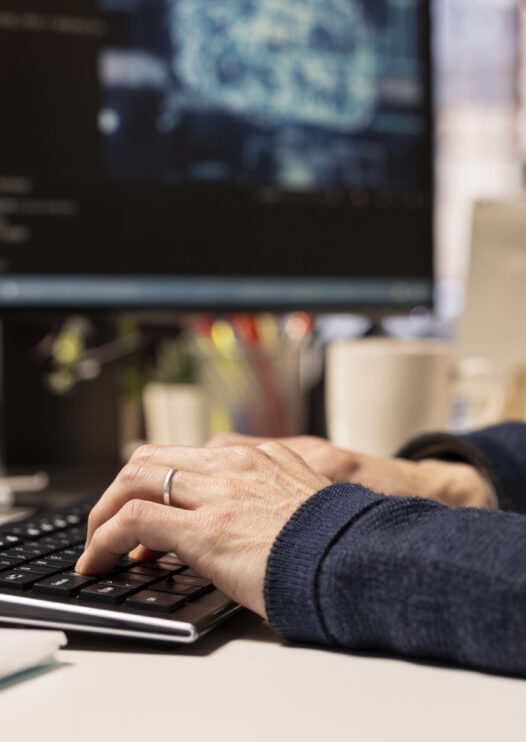 Startup programmer leveraging artificial intelligence tech in office to gain competitive edge. Close up of AI specialist typing on PC keyboard, working on rapid technological advancement